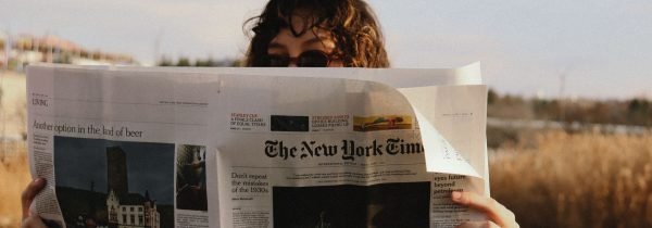 A person reads The New York Times outside on a sunny day, capturing a moment of leisure. — Crypto casino on mobile