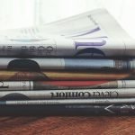 A stack of folded newspapers placed on a wooden table, symbolizing news and information. — Experience Baccarat Like Never Bef