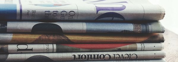 A stack of folded newspapers placed on a wooden table, symbolizing news and information. — Experience Baccarat Like Never Bef