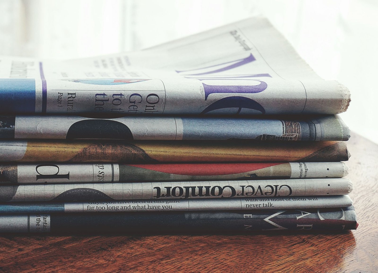 A stack of folded newspapers placed on a wooden table, symbolizing news and information. — Experience Baccarat Like Never Bef