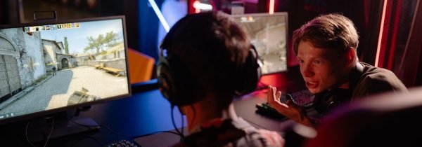 Two gamers engaged in a heated video game session surrounded by neon lights and computer screens. — Vivatbet Sportsbetting: B