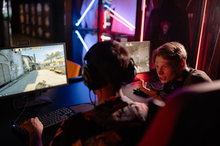 Two gamers engaged in a heated video game session surrounded by neon lights and computer screens. — Vivatbet Sportsbetting: B