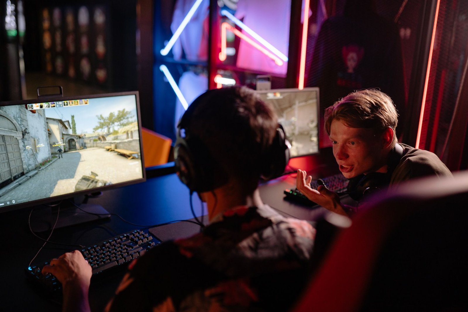 Two gamers engaged in a heated video game session surrounded by neon lights and computer screens. — Vivatbet Sportsbetting: B